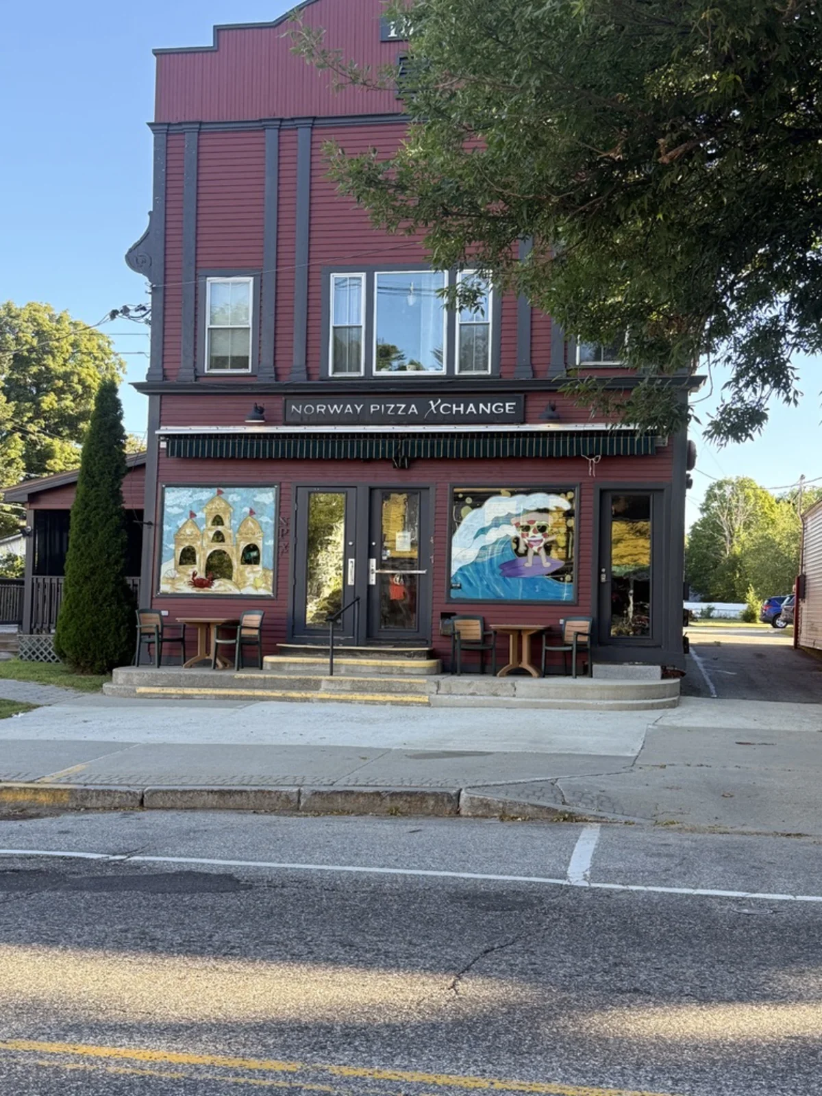 A red clapboard building on the same street housing the Norway Pizza Xchange, with painted murals either side of the door.
